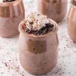 A glass cup of Chocolate Protein Pudding with whipped cream on top.