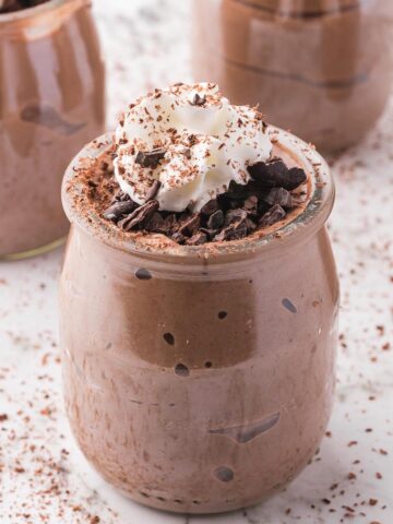 A glass cup of Chocolate Protein Pudding with whipped cream on top.