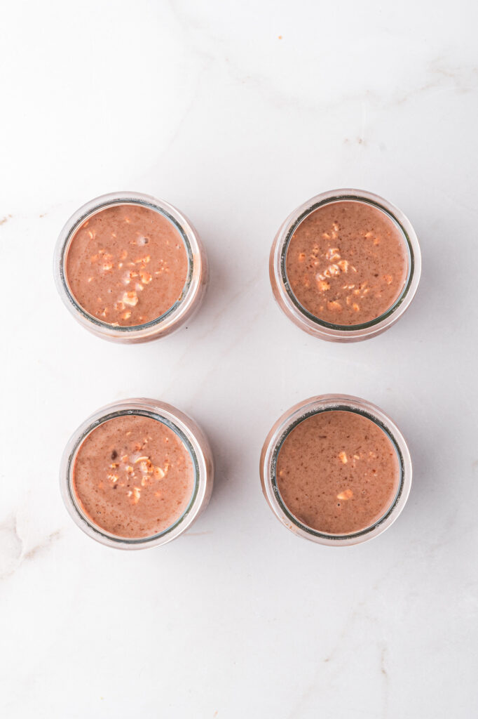 The overnight oat mixture divided into four glass jars.