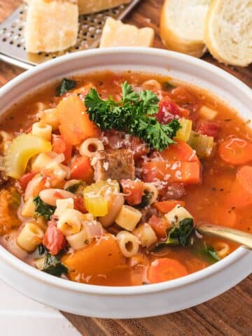 A bowl of Sausage Minestrone Soup with a spoon in it.