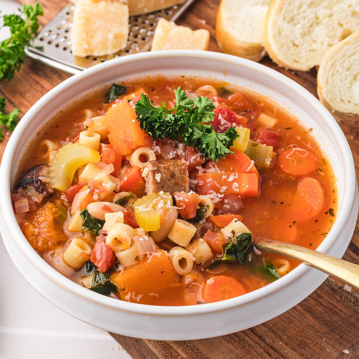 A bowl of Sausage Minestrone Soup with a spoon in it.