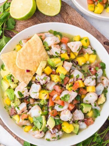 A bowl of Shrimp Mango Ceviche with a couple tortilla chips tucked inside.