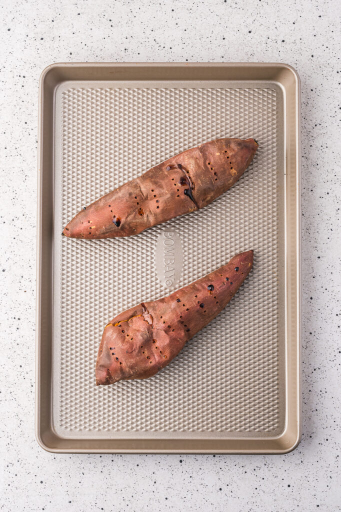 Two baked sweet potatoes on a baking sheets.