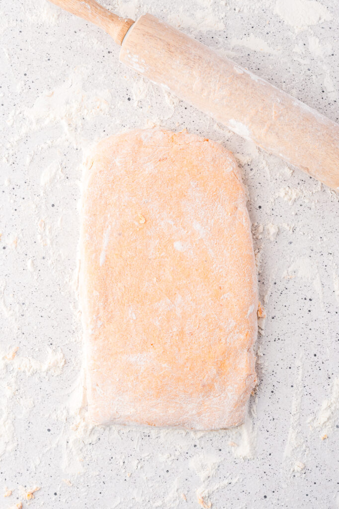 The sweet potato gnocchi dough rolled out into a rectangle on a floured surface.