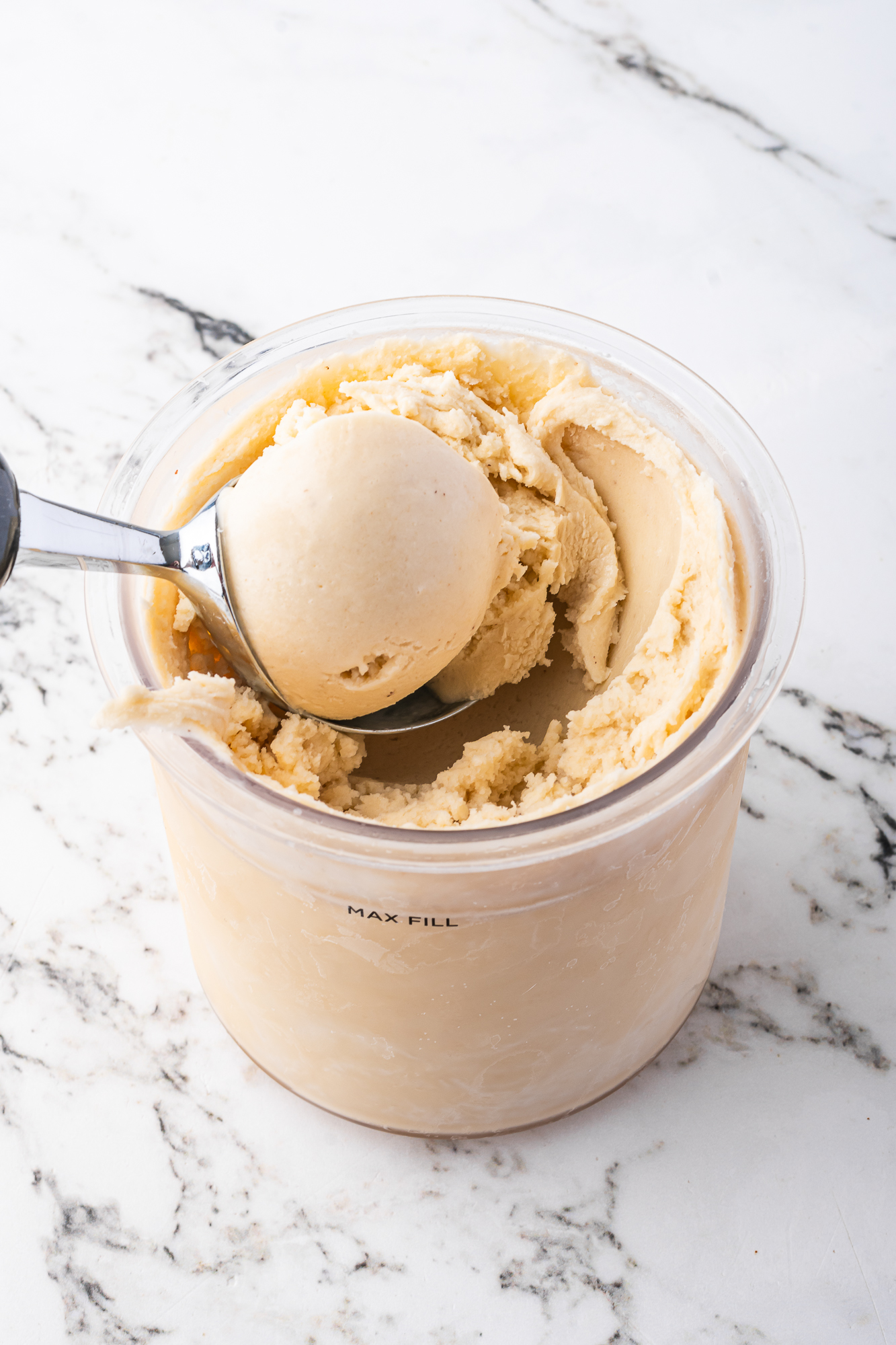 An ice cream scooper scooping the Ninja Creami Banana Ice Cream out of the container.