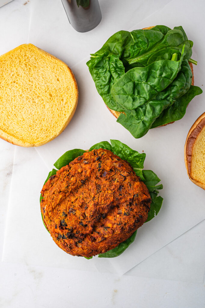 A hamburger bun with a leaf of lettuce topped with a Sweet Potato and Black Bean Burger