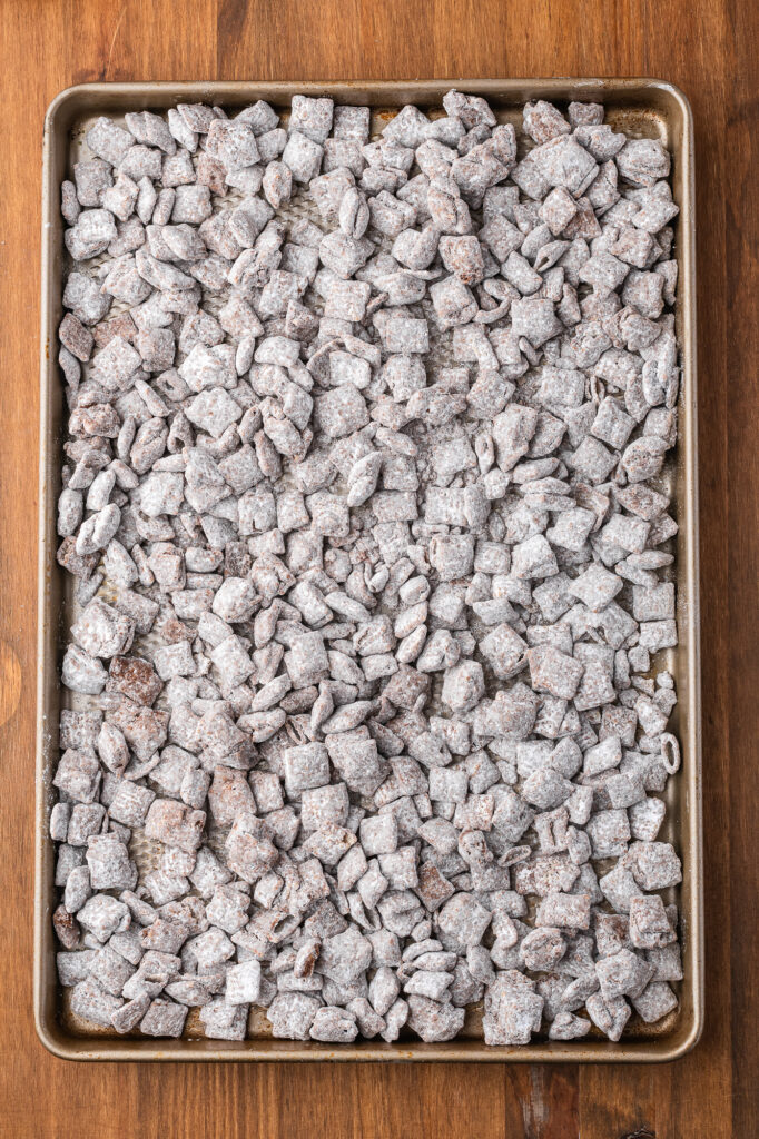 Powdered sugar-coated chocolate-covered Chex on a baking sheet