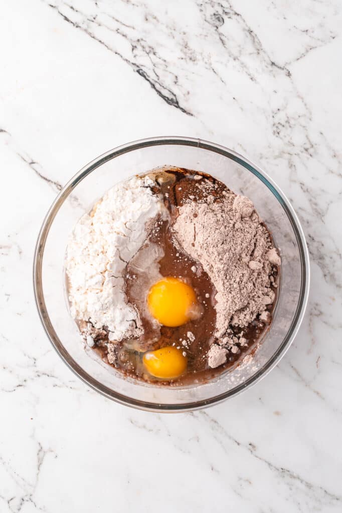 A glass mixing bowl full of all the ingredients for Easy Brownie Mix Cookies