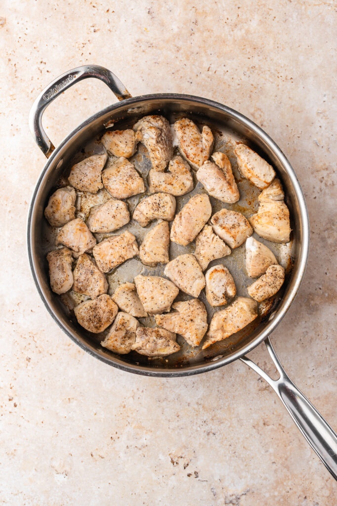 A skillet of browning chicken breasts pieces