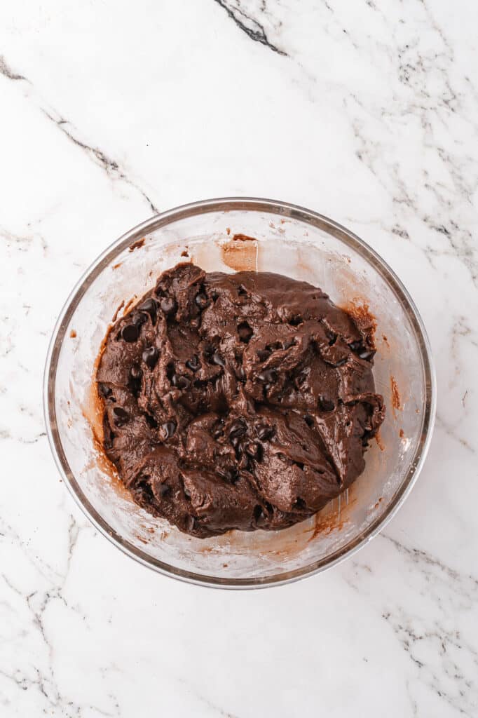 A glass bowl full of Easy Brownie Mix Cookies batter with chocolate chips