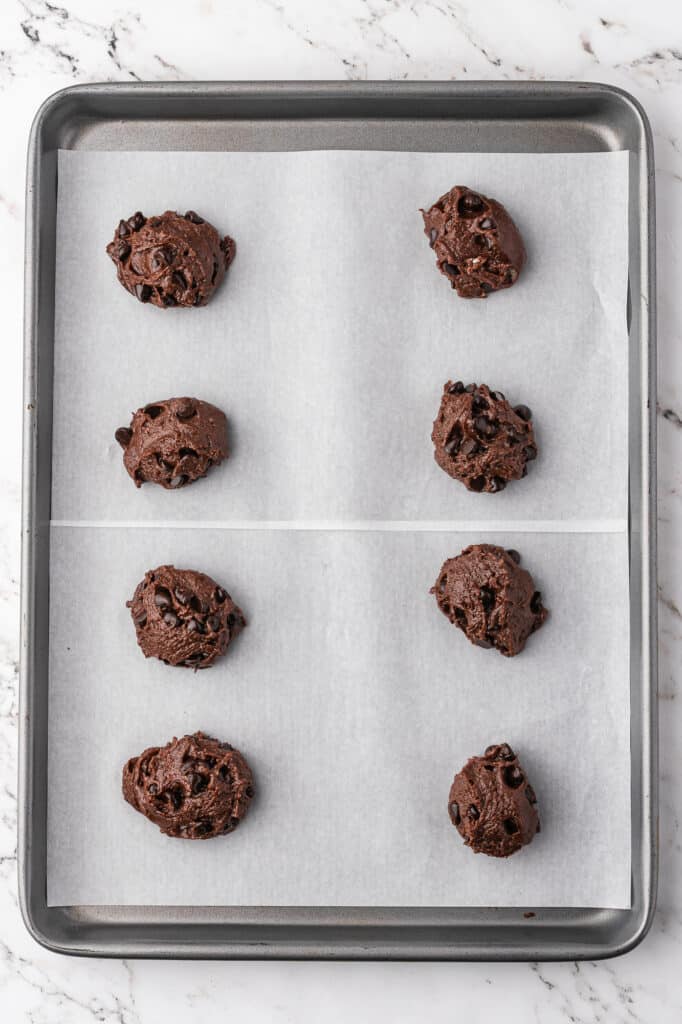 A parchment-lined baking sheet with 8 balls of Easy Brownie Mix Cookies dough