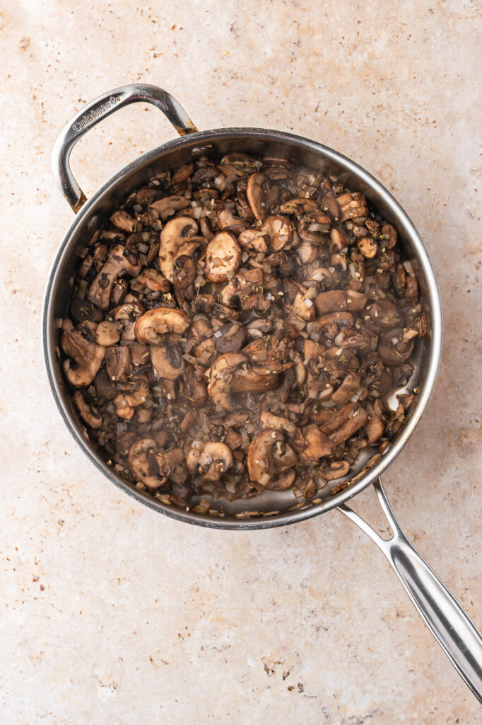 A skillet with a sliced mushroom and rice mixture cooking down