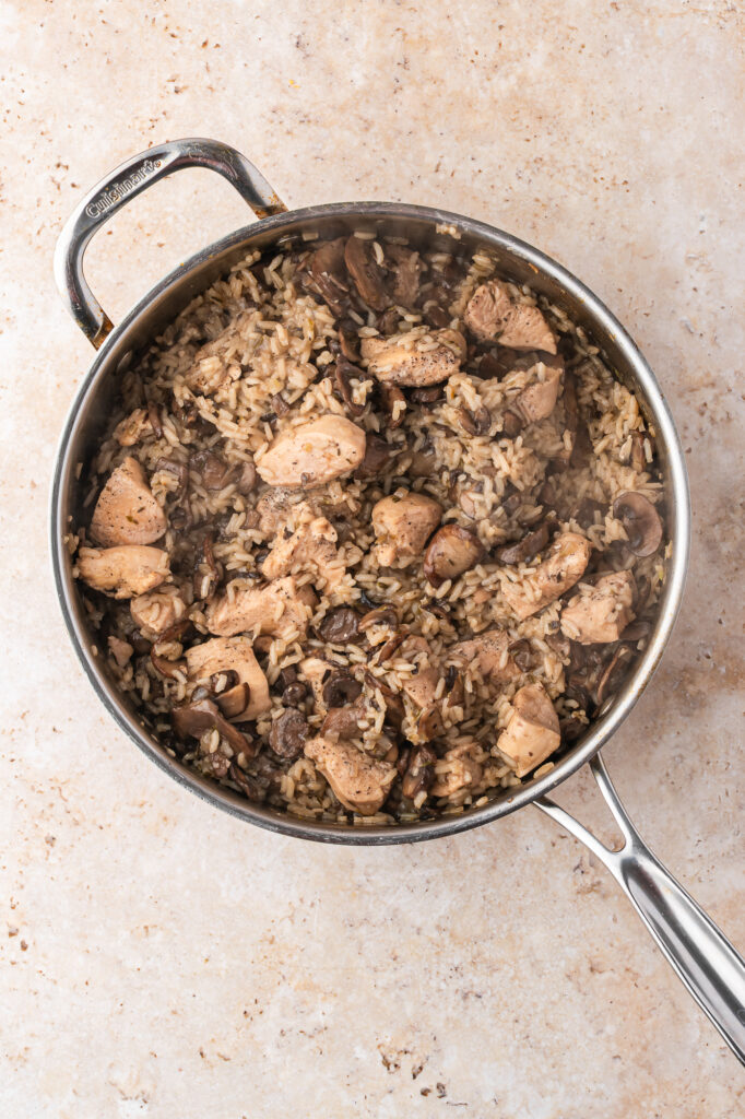 A skillet of cooking Creamy Mushroom Chicken and Rice