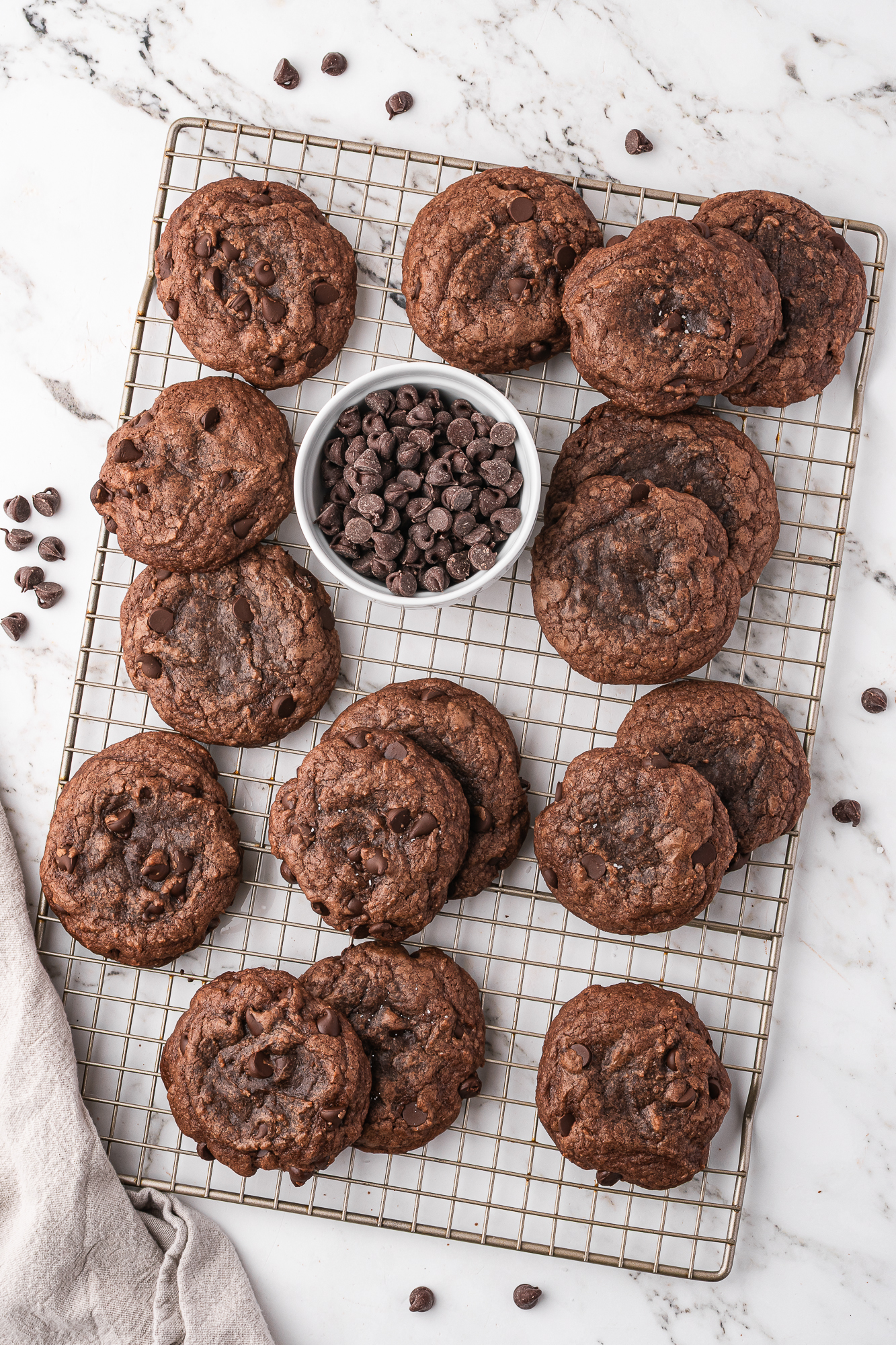 A cooling rack filled with Easy Brownie Mix Cookies and a bowl of chocolate chips