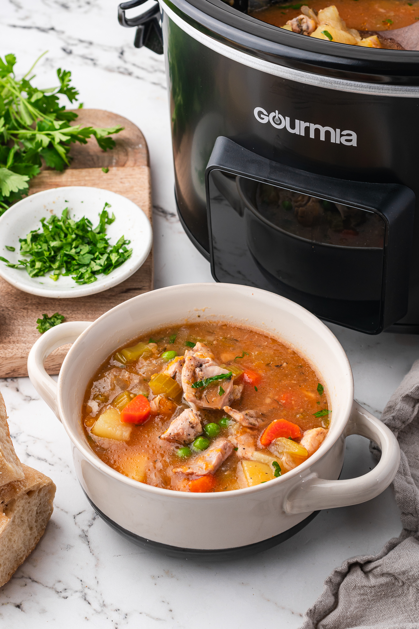 A bowl of Slow Cooker Hearty Chicken Stew in front of the slow cooker