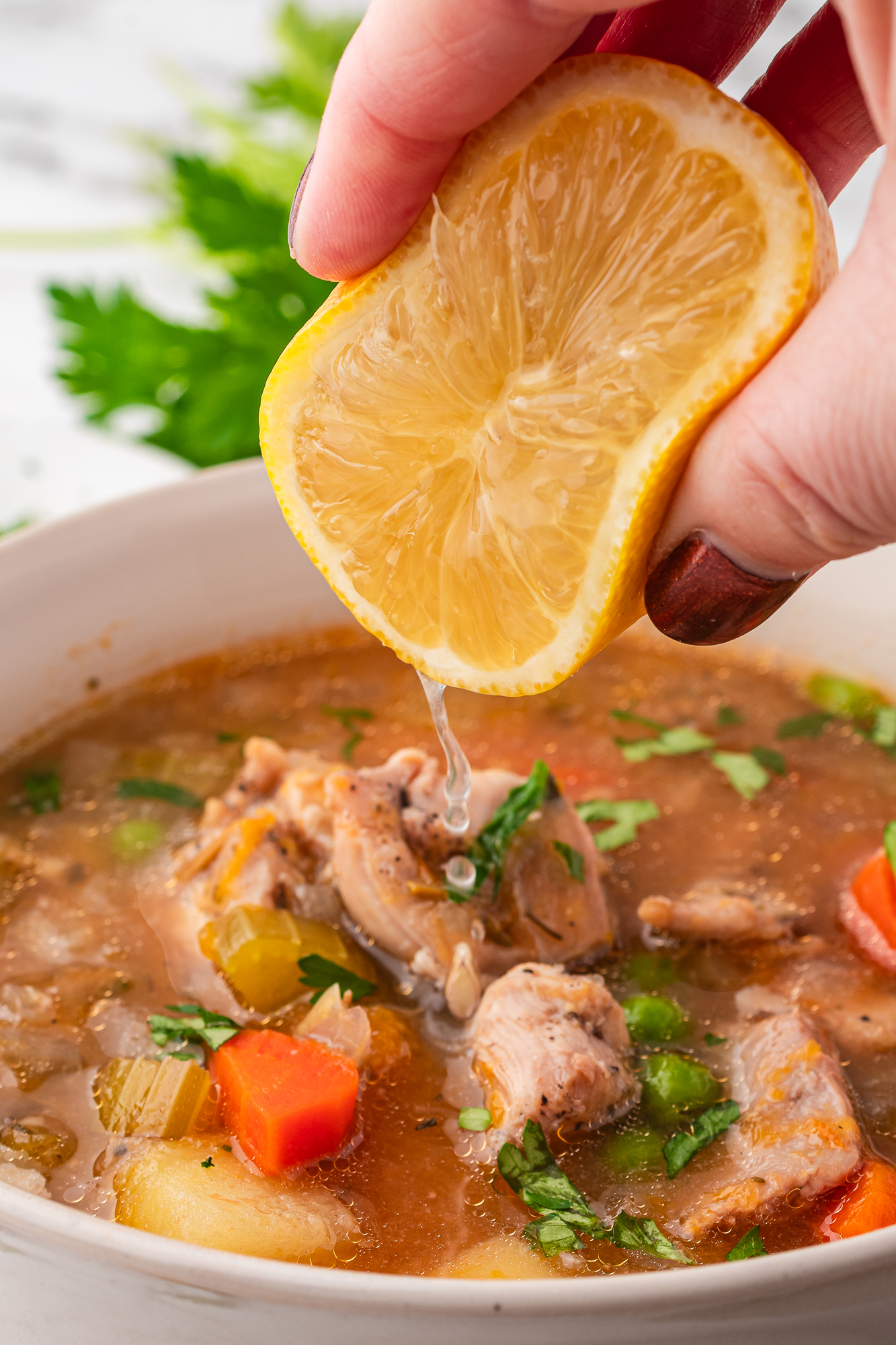 A lemon squeezing lemon juice of a bowl of Slow Cooker Hearty Chicken Stew