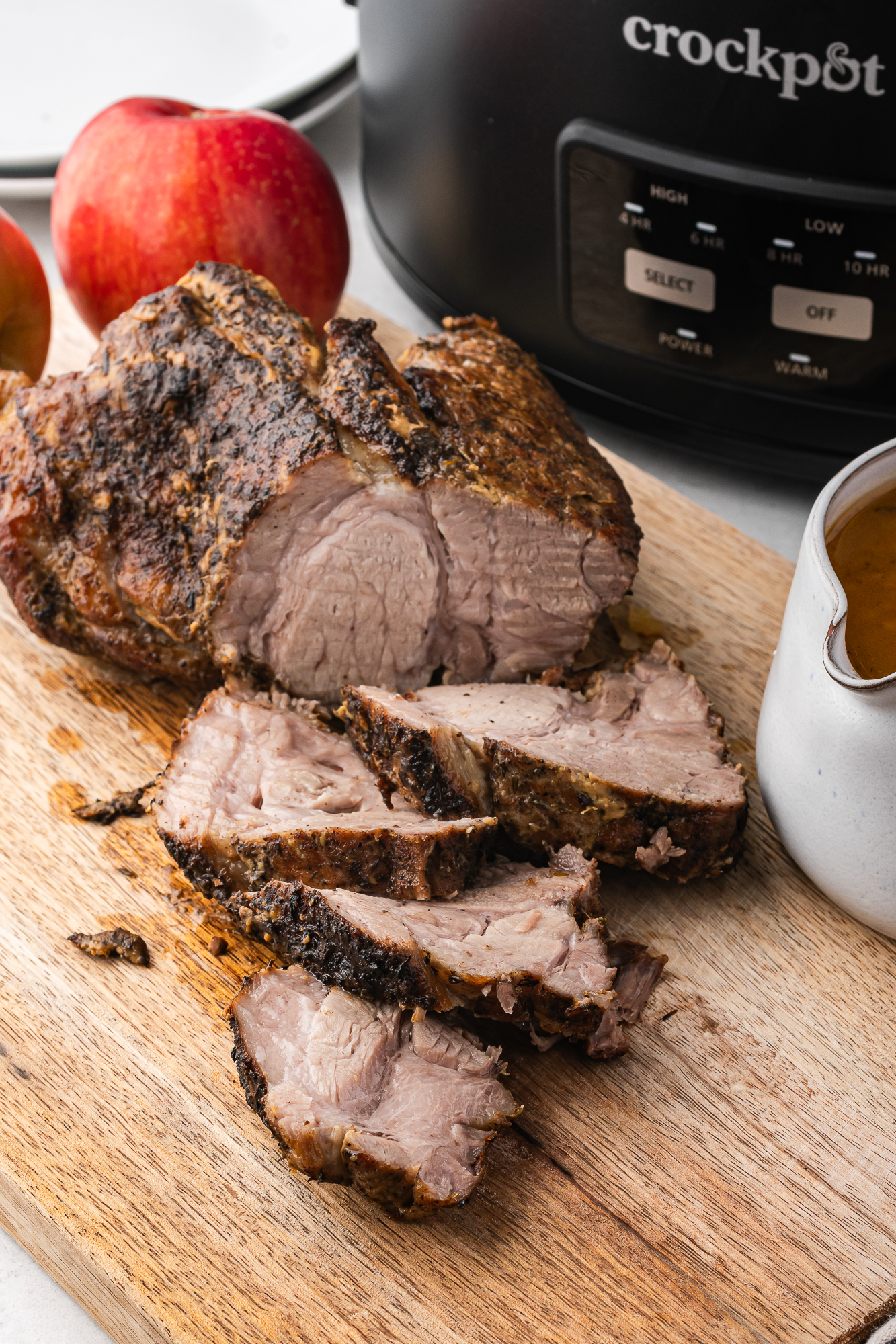 The pork being sliced on a wooden cutting board