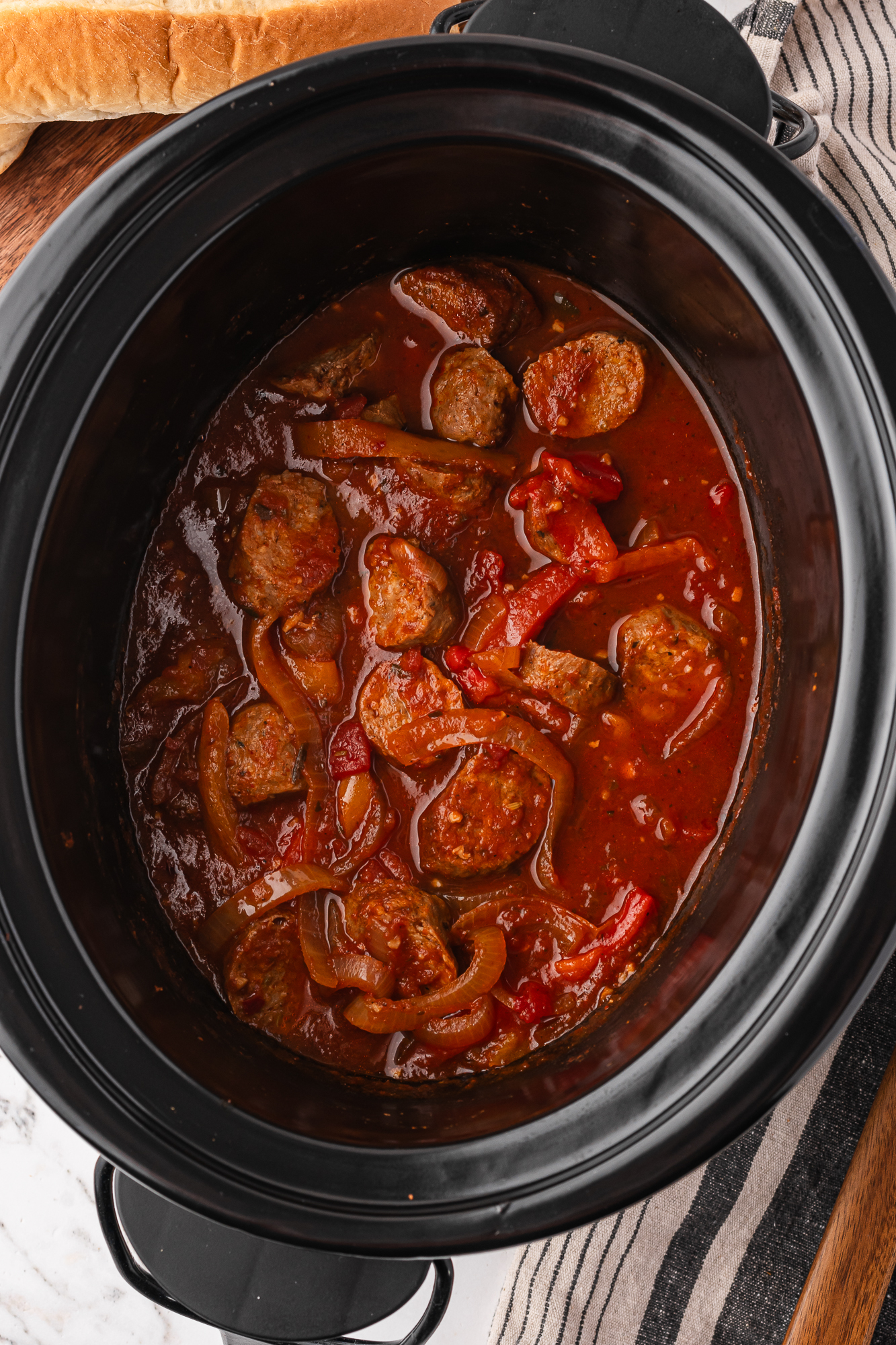 The slow cooker with the completed Slow Cooker Sausage and Peppers and the sausage sliced and mixed back in