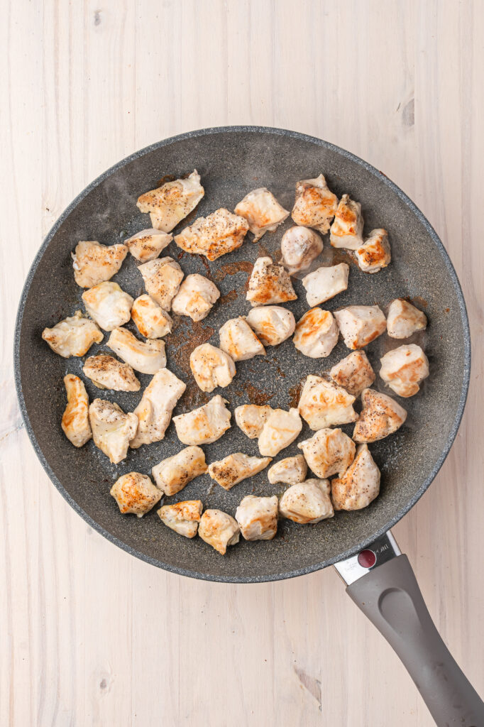 A skillet of cubed, seared chicken