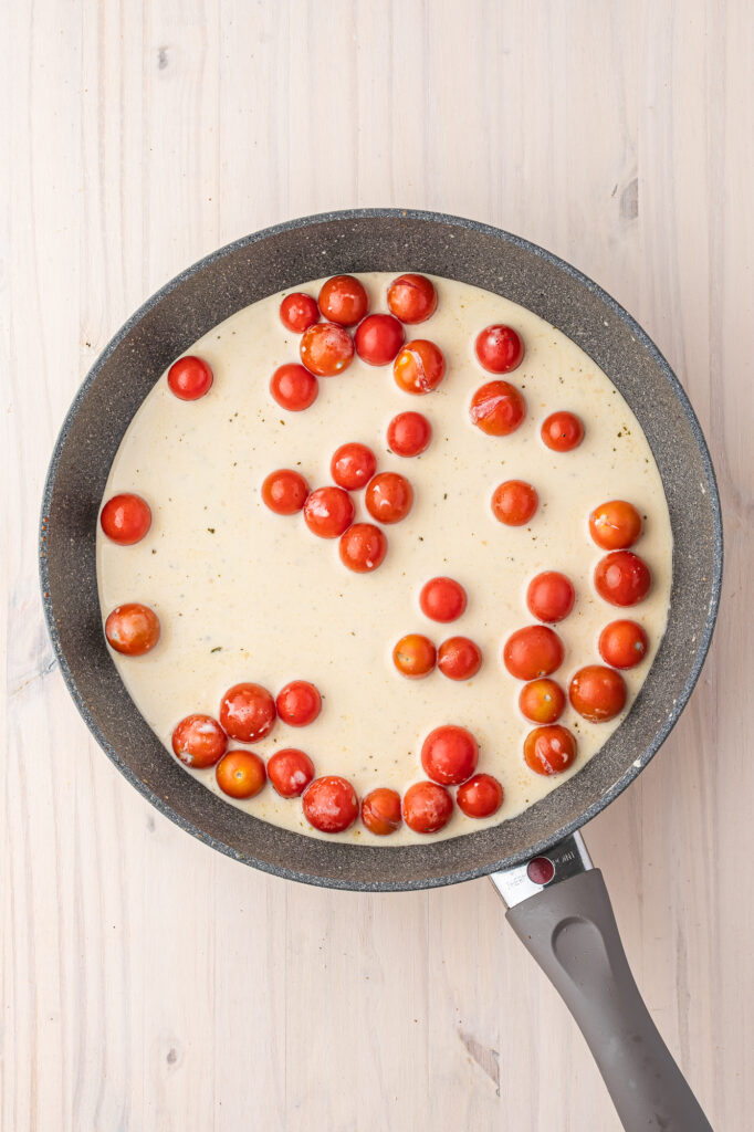 A skillet with cherry tomatoes and sauce in it