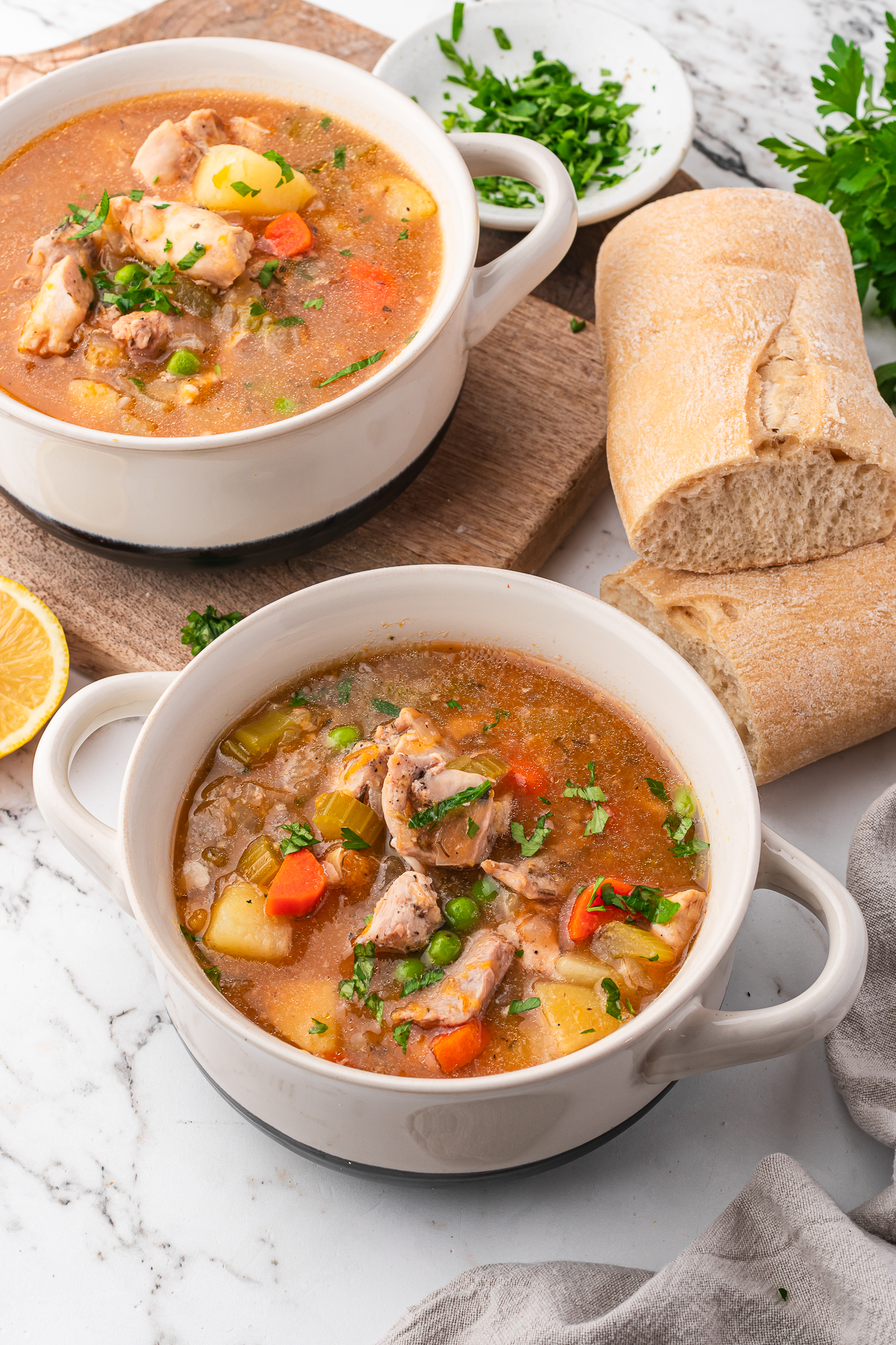 Two bowls of Slow Cooker Hearty Chicken Stew served with some rustic bread