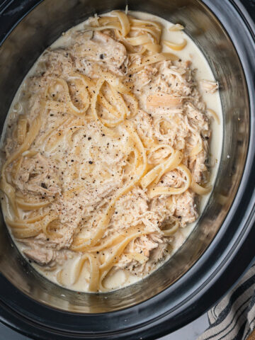 A slow cooker base with cooked Slow Cooker Chicken Alfredo