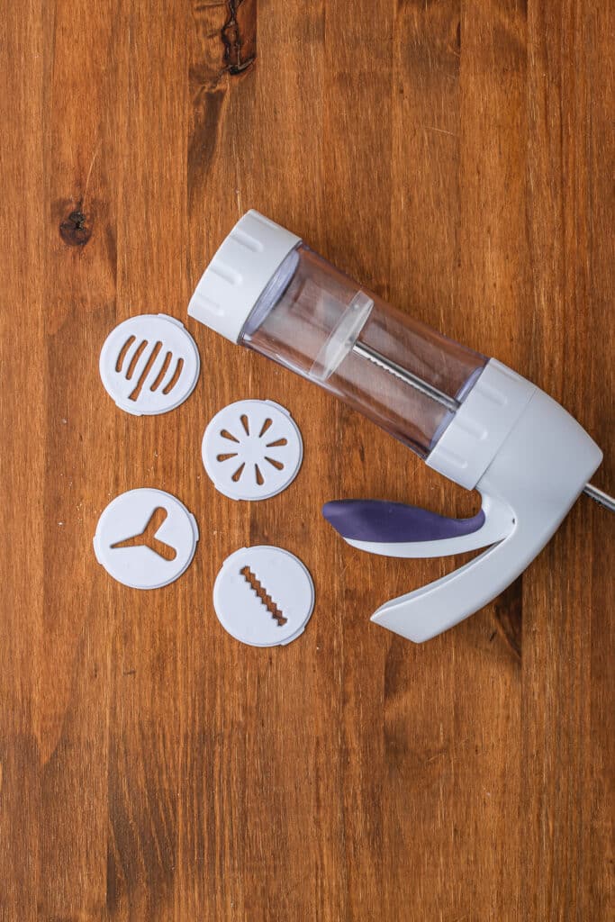 A cookie press laying on its side with four different attachments.