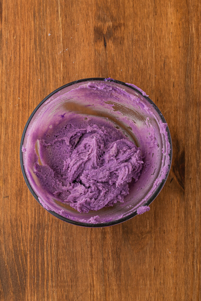 A small glass bowl filled with purple cookie dough.