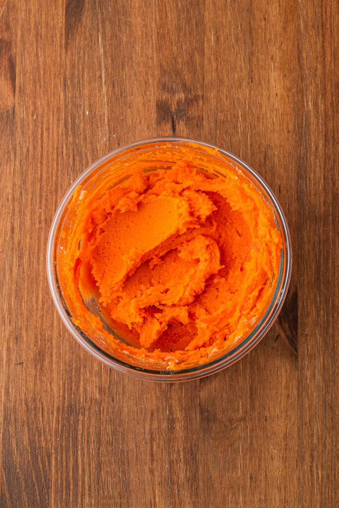 A small glass bowl filled with orange cookie dough.