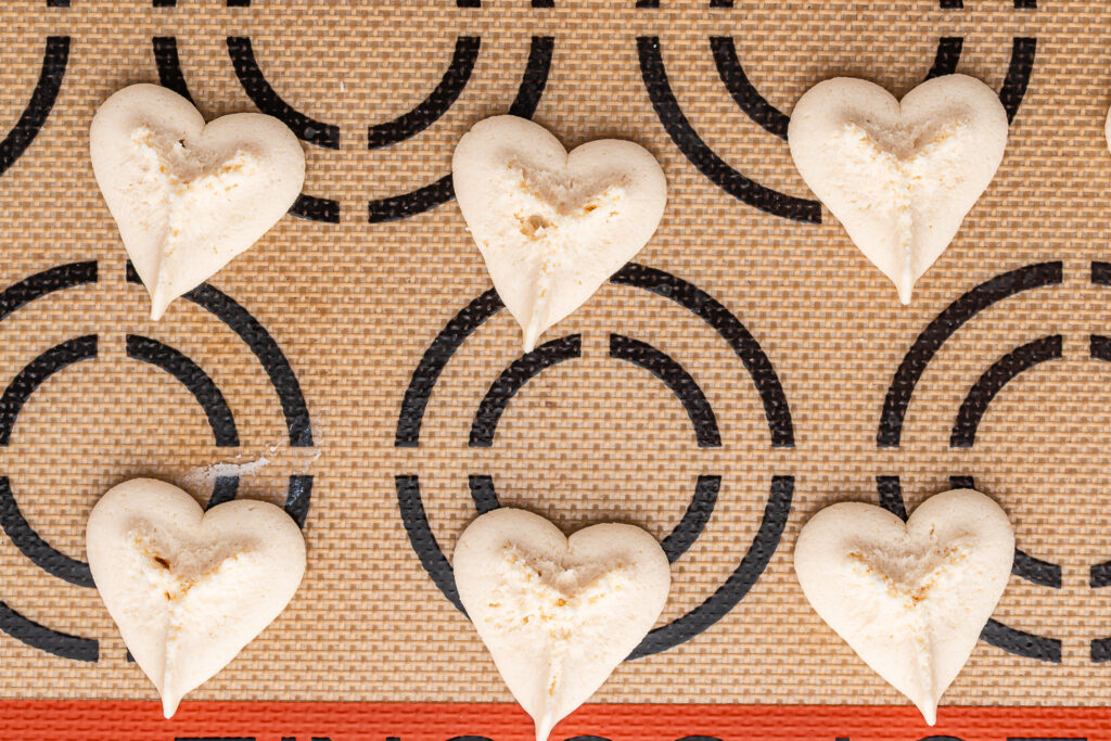 Heart-shaped cookie dough shaped pressed onto a silicone baking mat.