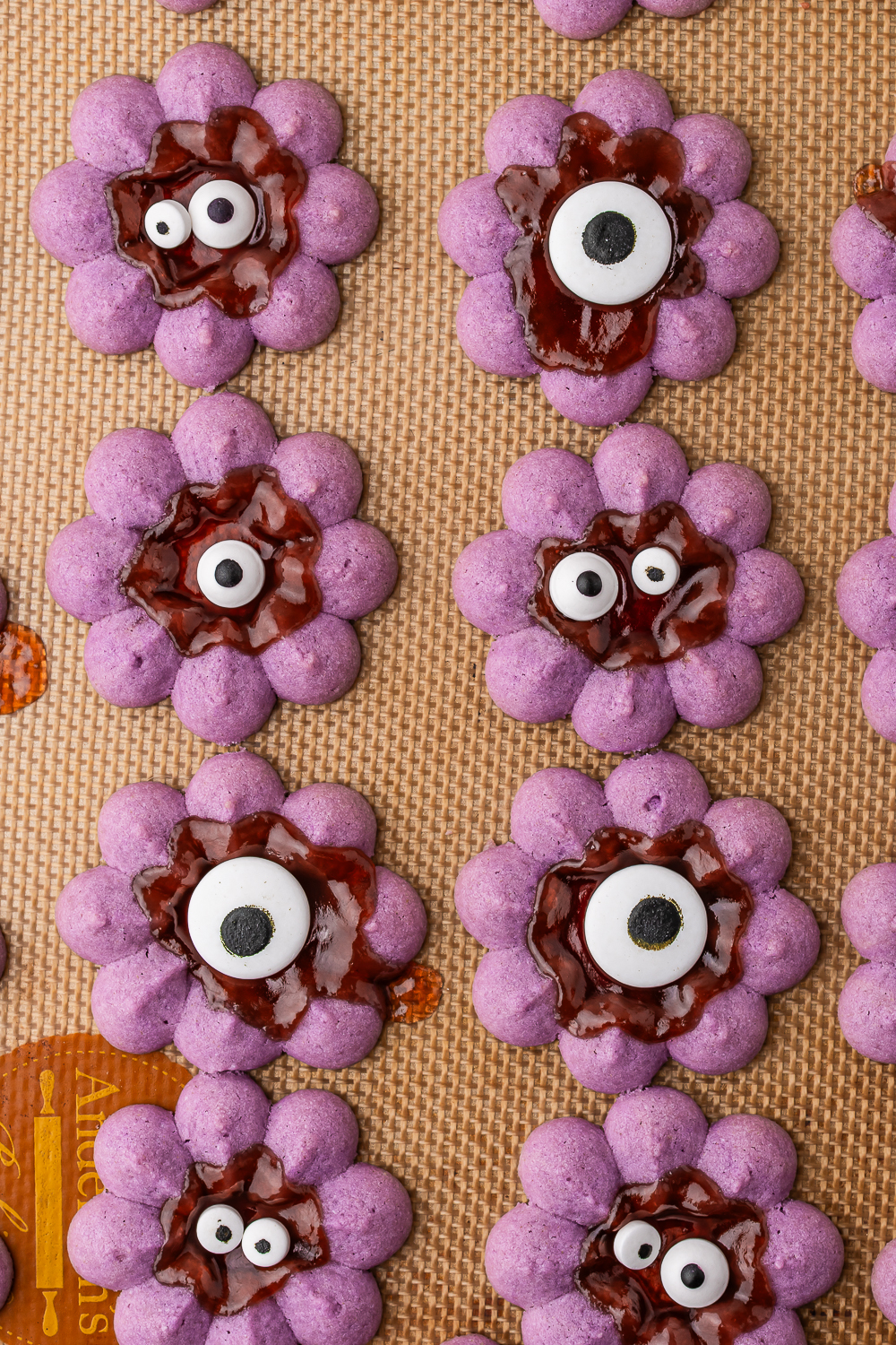 The final baked purple wreath-shaped Halloween Spritz Cookies with the jam in the center decorated with eyeball candy.
